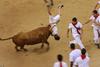 A reveller gored by a  bull on the final bull run of the San Fermin Festival in Pamplona